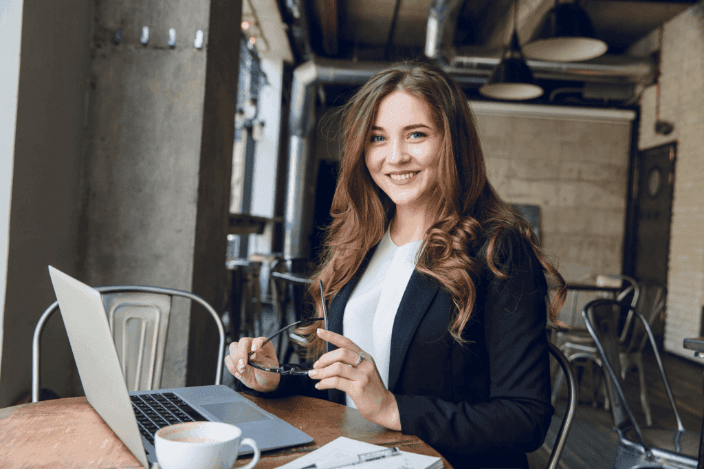 widely-smiling-businesswoman-working-laptop-sitting-cafe